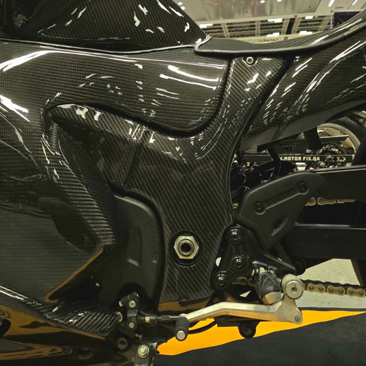 Close-up of a black motorcycle with carbon fiber texture in an indoor setting